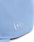 Closeup view of light blue new era flag on a same color fitted hat