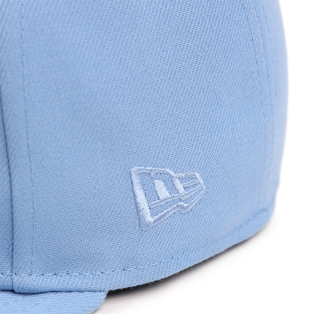 Closeup view of light blue new era flag on a same color fitted hat